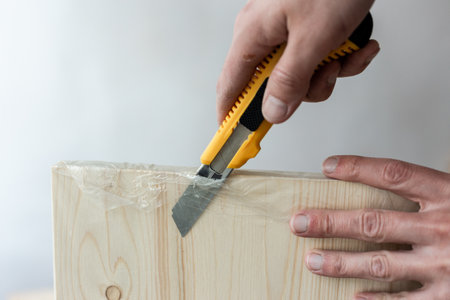 Unpacking a furniture board with a knife. Unpacking a wooden board.