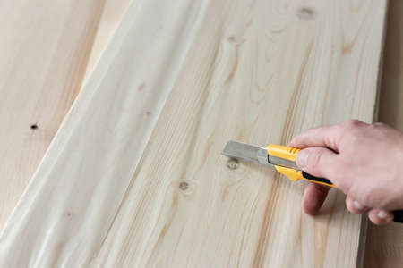 Unpacking a furniture board with a knife. Unpacking a wooden board.の写真素材