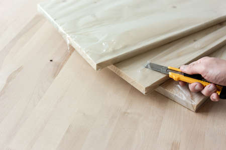 Unpacking a furniture board with a knife. Unpacking a wooden board.の写真素材