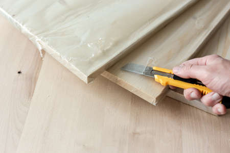 Unpacking a furniture board with a knife. Unpacking a wooden board.の写真素材