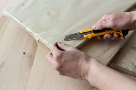 Unpacking a furniture board with a knife. Unpacking a wooden board.の写真素材