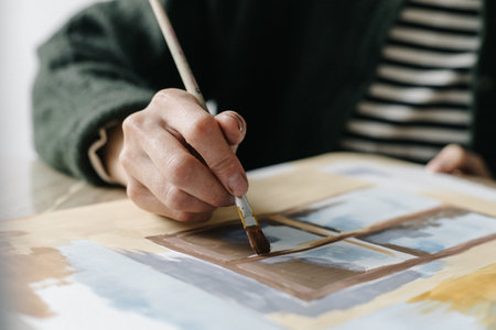 Woman paints with a brush paints on a sheetの写真素材