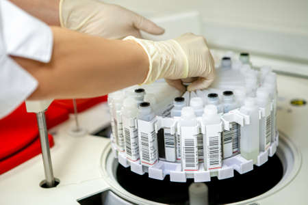 Laboratory assistant places labeled samples in a centrifuge, side view, close-up