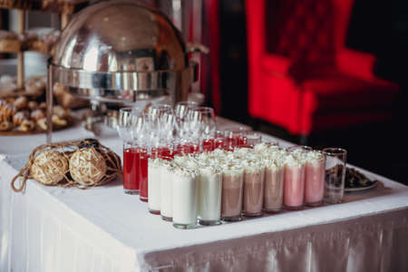 Candy bar on birthday party with a lot of different candies, cupcakes, souffle and cakes, milkshakes and juice in glass cups. Decorated on wooden stands, nature and eco theme, indoorの写真素材