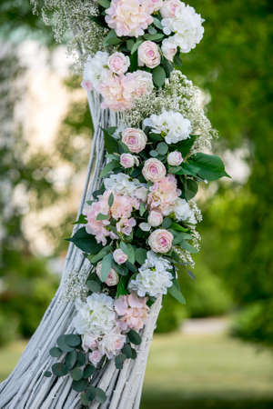 Summer outdoor wedding ceremony decoration. Decoration of white roses, hydrangeas and gypsophila on the arch for the wedding ceremony. Vertical view.の写真素材