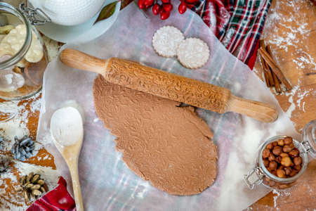 Rolling pin with a pattern on a wooden decorated table covered with baked flour. Rolled dough with a...