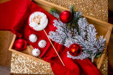 Gingerbread Santa on a stick on the breakfast table with fir branches and red ball on a background, top view. Holiday sweets. New Year and Christmas theme. Festive mood. Christmas Card.の写真素材