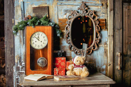Teddy bear, gifts, books, vintage clock and mirror on a wooden background in the room decorated for...
