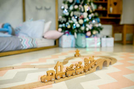 Children bedroom decorated for Christmas. Wooden toy railway on the background of the Christmas tree lights and bed. Christmas morning. Holiday mood.の写真素材