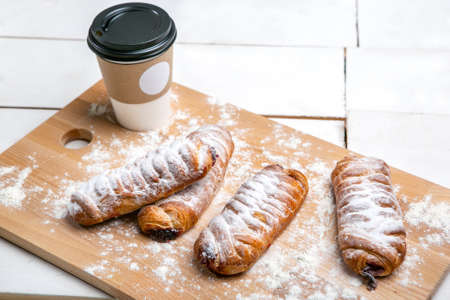 Cup of hot coffee with cakes on the wooden table on white background. Fast breakfast. French...