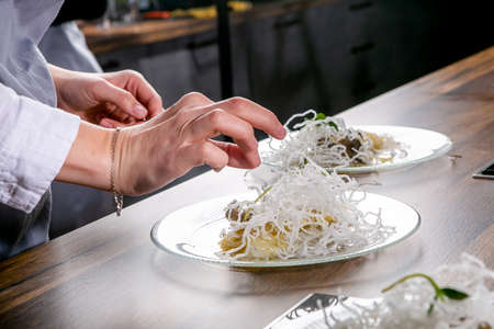 Chef decorates the halibut with mango sauce and rice noodles. Master class in the kitchen. The...