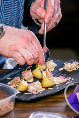 Chef decorates the dish from smoked catfish and baked quince. Master class in the kitchen. The...