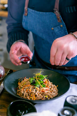 Chef decorates the buckwheat noodles with duck and mushroom. Master class in the kitchen. The...