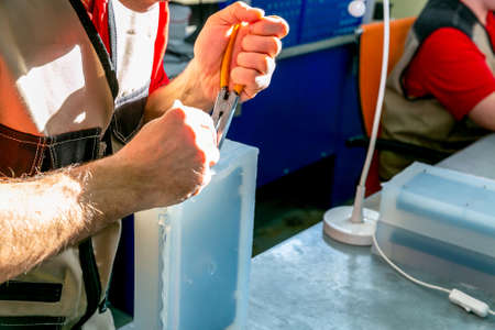 A worker extract the plastic detail from the mold. Manufacturing of plastic products. Medium...