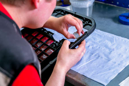 A worker sanding a plastic blank. Manufacturing of plastic products. Medium business concept. Hands...