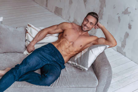 Portrait of strong healthy handsome athletic man. Fitness model posing and smiling while lying on...