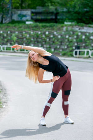 Fitness lifestyle. Young woman warming up before training doing exercises to stretch her muscles and joints. Workout at the stadium. Healthy life concept.の写真素材