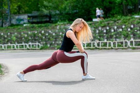 Fitness lifestyle. Young woman doing lunges to the side. Workout at the stadium. Healthy life...