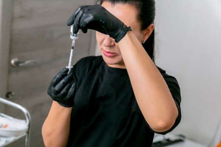 Beautician dials an injection of botulinum toxin into the syringer. Young woman on cosmetological...