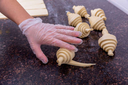 A pastry chef in the kitchen is making pastries. Chef rolls the cut dough into a croissant. Master...