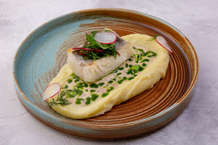 Cod with mashed potatoes, zucchini grill and sauce on the light background. European cuisine. The...