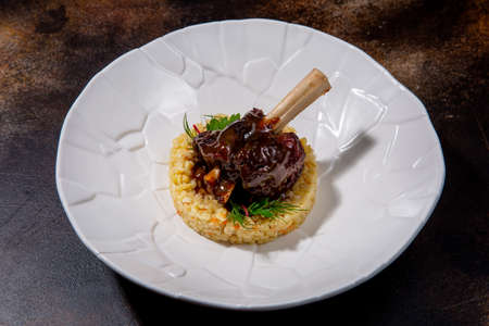 Lamb with bulgur and balsamic sauce. Lamb on the bone, bulgur, balsamic cream, arugula and zucchini. European cuisine. The work of a professional chef. Dish from a restaurant menu. Side view.の写真素材