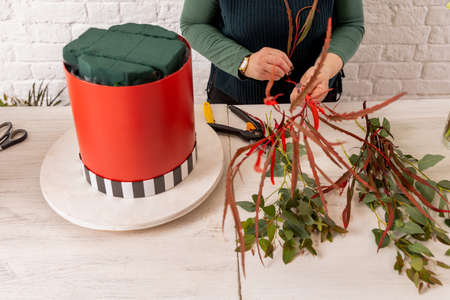 Florist workplace on the background of a white brick wall. An experienced florist prepares the base...