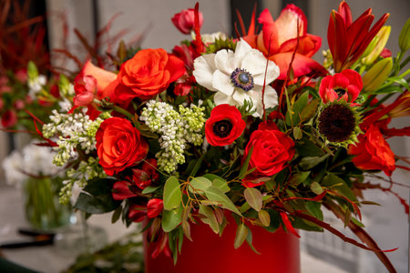 Flower arrangement in red shades of orchids, roses, sunflowers, lilies, alstroemerias and ornithogalums in a red box. Professional florist work.の写真素材