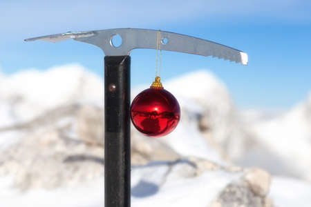 Christmas ornament hanging from the pick of the ice axe with magnificent snow covered mountains. The best way to start a new year is a good hike to mountains.の写真素材