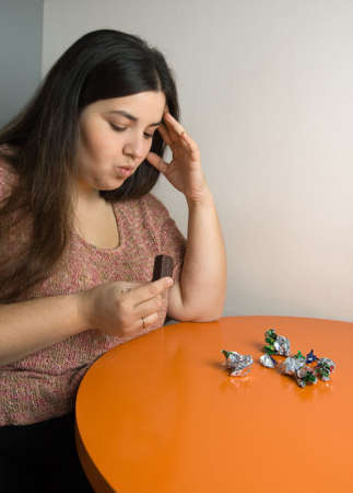 woman contemplating over wrappers of sweetsの写真素材