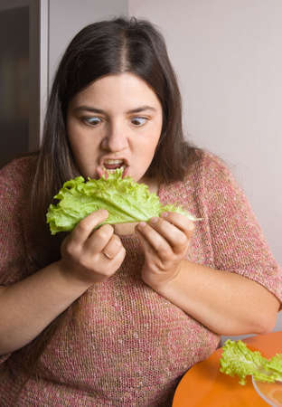 woman trying to eat a leaf of lettuceの写真素材