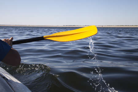 Kayak paddle on side of a boat at still river waterの写真素材