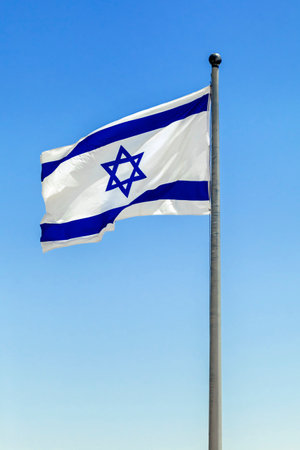 The Israeli flag waves in the bright sunlight, its blue Star of David prominent against the white backgroundの写真素材
