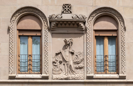 Intricate stone relief showcases a figure next to decorative windows in daylight.の写真素材