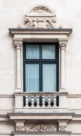 A beautifully crafted window with ornate columns and decorative motifs showcases classic architecture in a city building.の写真素材