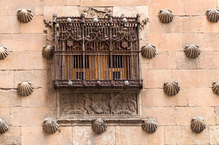 A detailed view of a historic stone building in Salamanca, featuring a decorative window with...