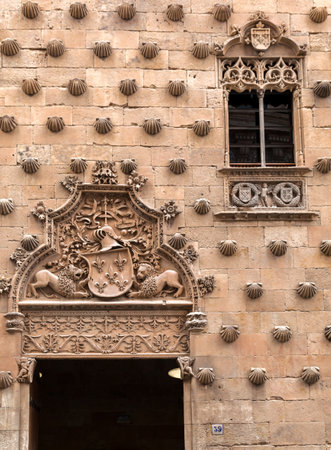 A detailed view of a historic stone building in Salamanca, featuring a decorative window with intricate ironwork.の写真素材