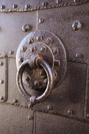 A close-up of a decorative iron door knocker on a weathered door in an old urban setting.の写真素材