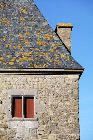 Stone building featuring distinct architectural details against a clear blue sky.の写真素材