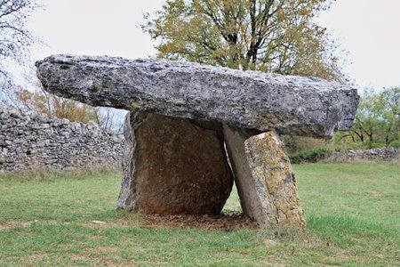 Visitors observe a prehistoric dolmen nestled in serene natural surroundings within Sarlat-la-Caneda, France.の写真素材