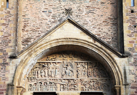 Detailed stone sculptures at the church entrance in Conques highlight medieval craftsmanship and artistic expression.の写真素材