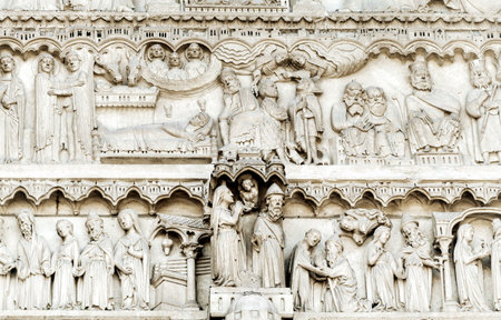 Detailed stone reliefs depict various biblical stories and figures on the Notre-Dame de Paris facade.の写真素材
