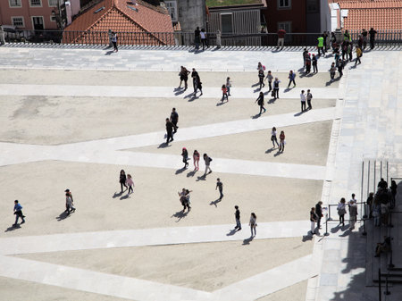 Coimbra, Portugal - April 3, 2017 - People walk across a large, geometric paved area in Coimbra, Portugal under a clear skyの写真素材