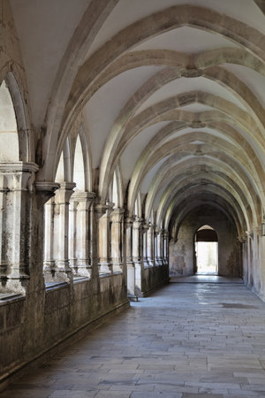 Intricate stone arches and columns in the beautiful cloister at Batalha monastery during daytimeの写真素材