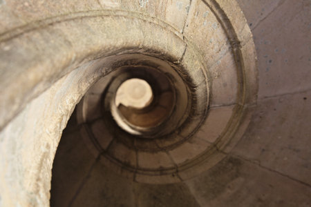 Visitors navigate the intricate spiral staircase at Convento de Cristo, showing historical...