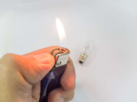 A hand holding a lit lighter, isolated on white background.