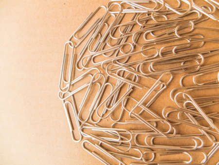 Paperclips on brown Background to keep sheets of paper together.の写真素材