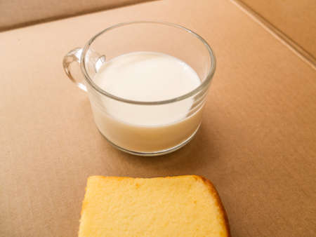 Glass of milk and sliced bread on brown paper backgroundの写真素材