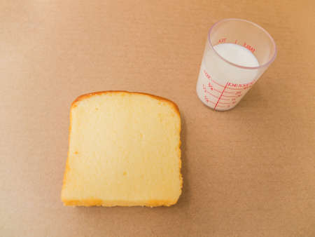 Glass of milk and sliced bread on brown paper backgroundの写真素材