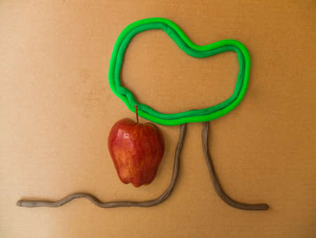 red apple and Plasticine tree on brown paper background の写真素材